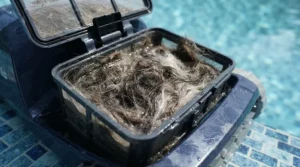 Close-up of a robotic pool cleaner for pets with hair in the pool showing a fine mesh filter basket.